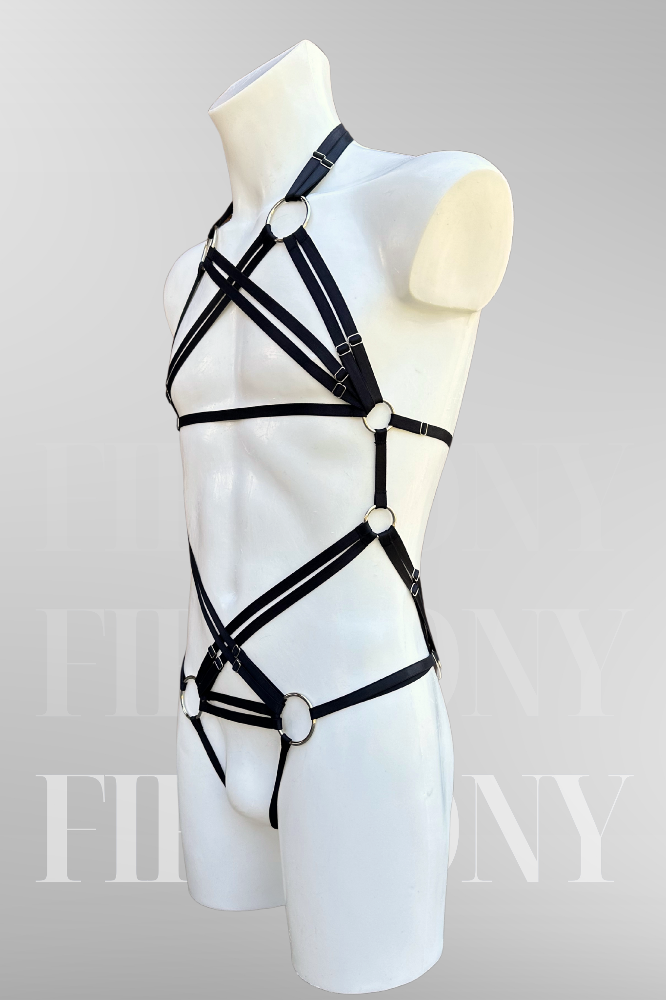Angled side view of the black elastic harness highlighting the chest, waist, and thong straps.
