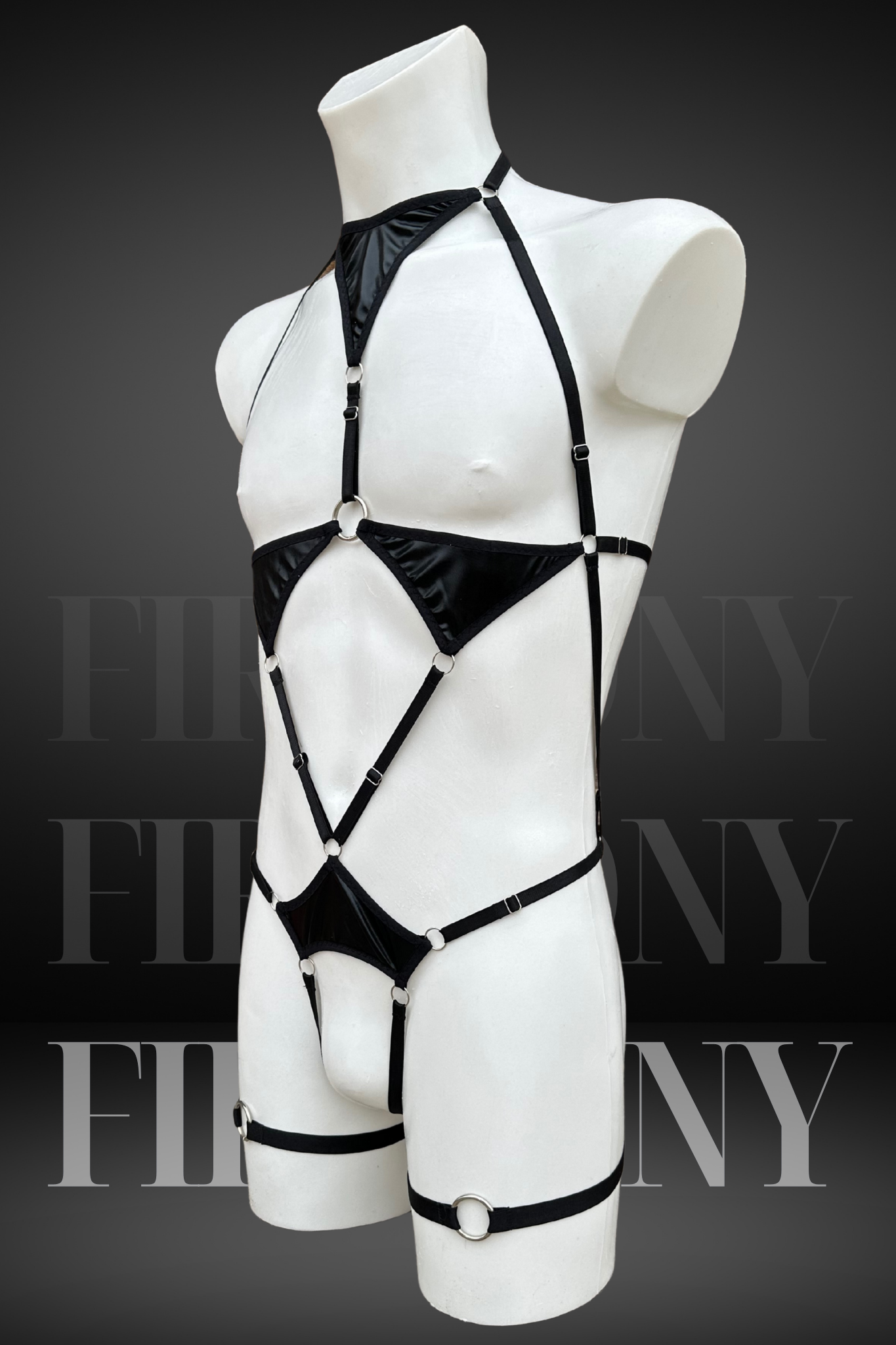 Side view of a black strappy wetlook bodysuit for men, showing metal rings and harness design.