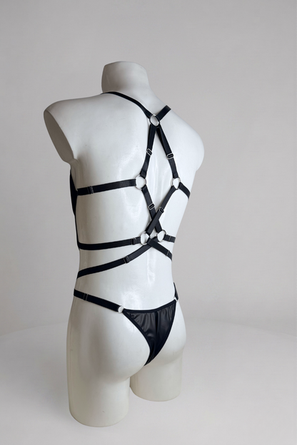 Side back view of men's vegan leather bodysuit: strap harness and thong cut