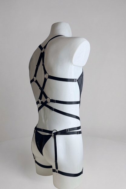 Side back view of black vegan leather bodysuit for men with garter belt: thong back, strap harness and thigh bands