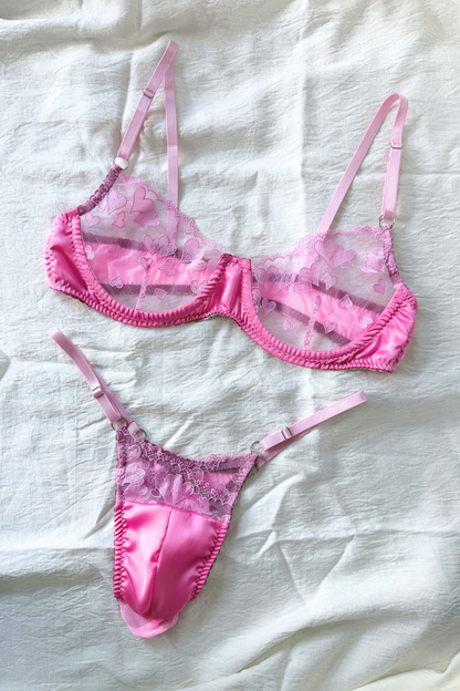 Soutien-gorge à armatures en dentelle cœur rose transparente et string à poche en satin pour homme, posés à plat