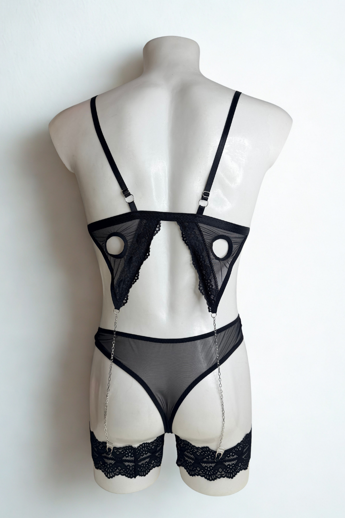 Back view of the black cage bra set for men: adjustable straps, sheer mesh thong back and lace thigh garters