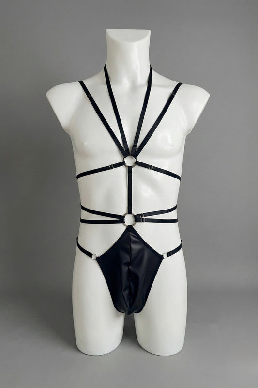 Black strappy harness bodysuit for men on mannequin - elastic straps with o-rings and faux leather thong, front view