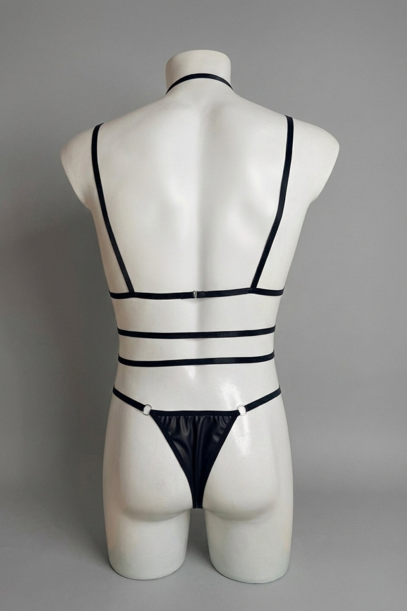 Back view of men's black strappy harness bodysuit - open strap back with thong bottom