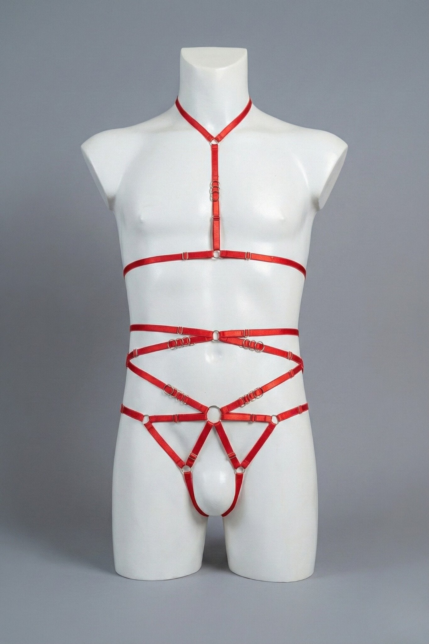 Red strappy body harness set for men on mannequin - choker harness top and open-frame harness bottom with silver o-rings, front view